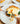 Close up view of hands cutting into a breakfast sandwich with fork and knife.