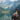 A dark-haired woman looks out over a scenic alpine lake.