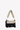 Angled front view of Sherpani's purse, the Skye in Con Leche. The bag is two-toned in black and beige. There is an external zipper compartment with an easy-pull zipper. There is a branded Sherpani keychain clipped to the upper right corner. The bag has a detachable short strap and a longer detachable/adjustable crossbody strap. #color_con-leche