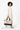 Model carrying the Sherpani Boston AT in Straw in her right hand, body turned slightly to the right. #color_straw