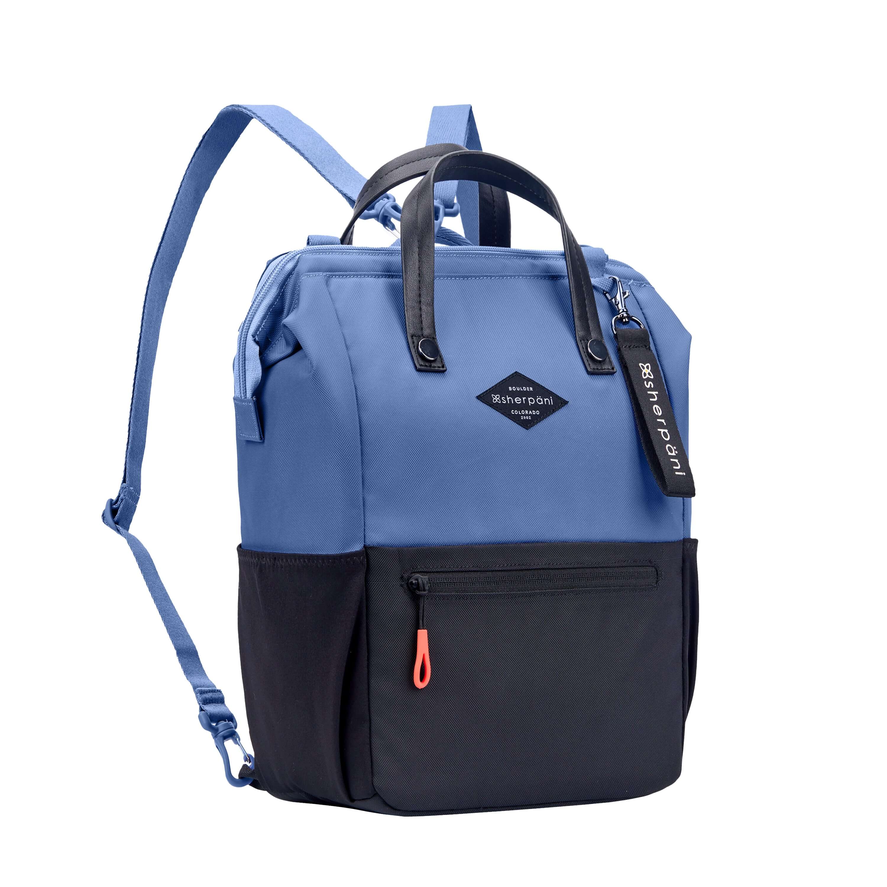 Angled front view of Sherpani three in one bag, the Dispatch in Pacific Blue. The bag is two toned: the top is ocean blue and the bottom is black. There is an external zipper pocket on the front panel. Easy pull zippers are accented in red. A branded Sherpani keychain is clipped to the upper right corner. Elastic water bottle holders sit on either side of the bag. It has short tote handles and adjustable/detachable straps that can function for a backpack or crossbody. 