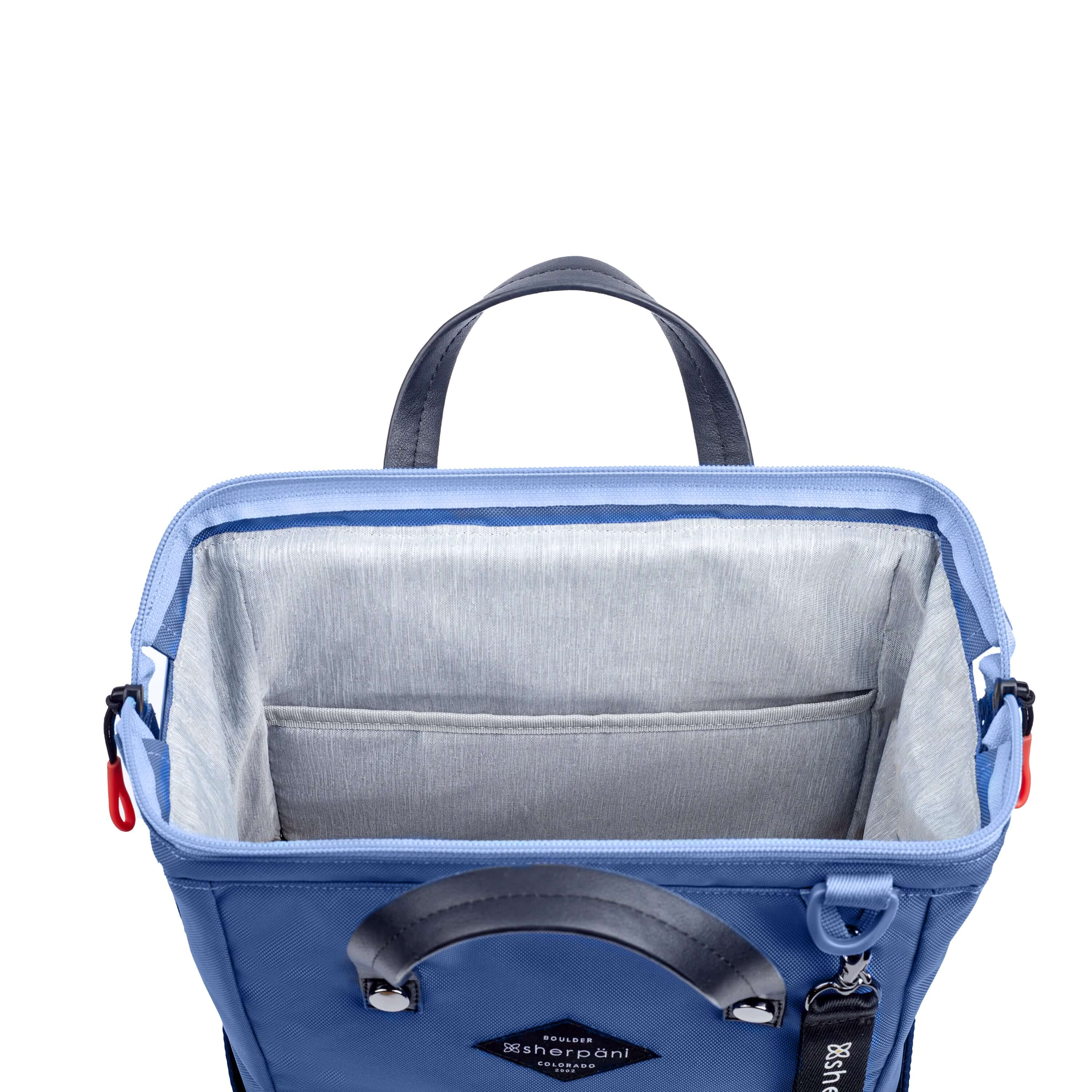 Top view of Sherpani three in one bag, the Dispatch in Pacific Blue. The main zipper compartment is open to reveal a doctor bag style opening with a rectangular metal frame. The inside of the bag is light gray and features an internal pouch. 