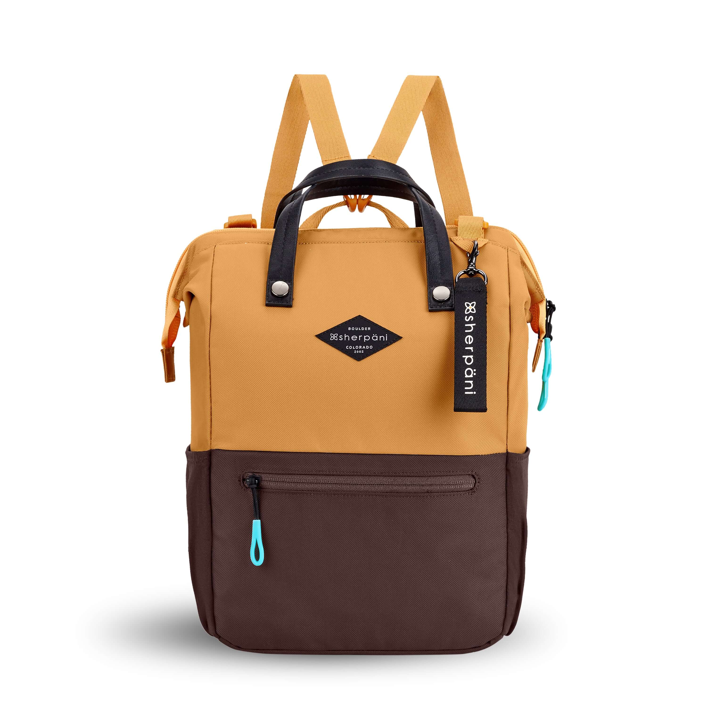 Flat front view of Sherpani three in one bag, the Dispatch in Sundial. The bag is two toned: the top is burnt yellow and the bottom is brown. There is an external zipper pocket on the front panel. Easy pull zippers are accented in aqua. A branded Sherpani keychain is clipped to the upper right corner. Elastic water bottle holders sit on either side of the bag. It has short tote handles and adjustable/detachable straps that can function for a backpack or crossbody. 