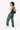 Model smiling over her left shoulder with one hand in her pocket, wearing the Sherpani sling bag, the Esprit in Con Leche on her back. #color_con-leche