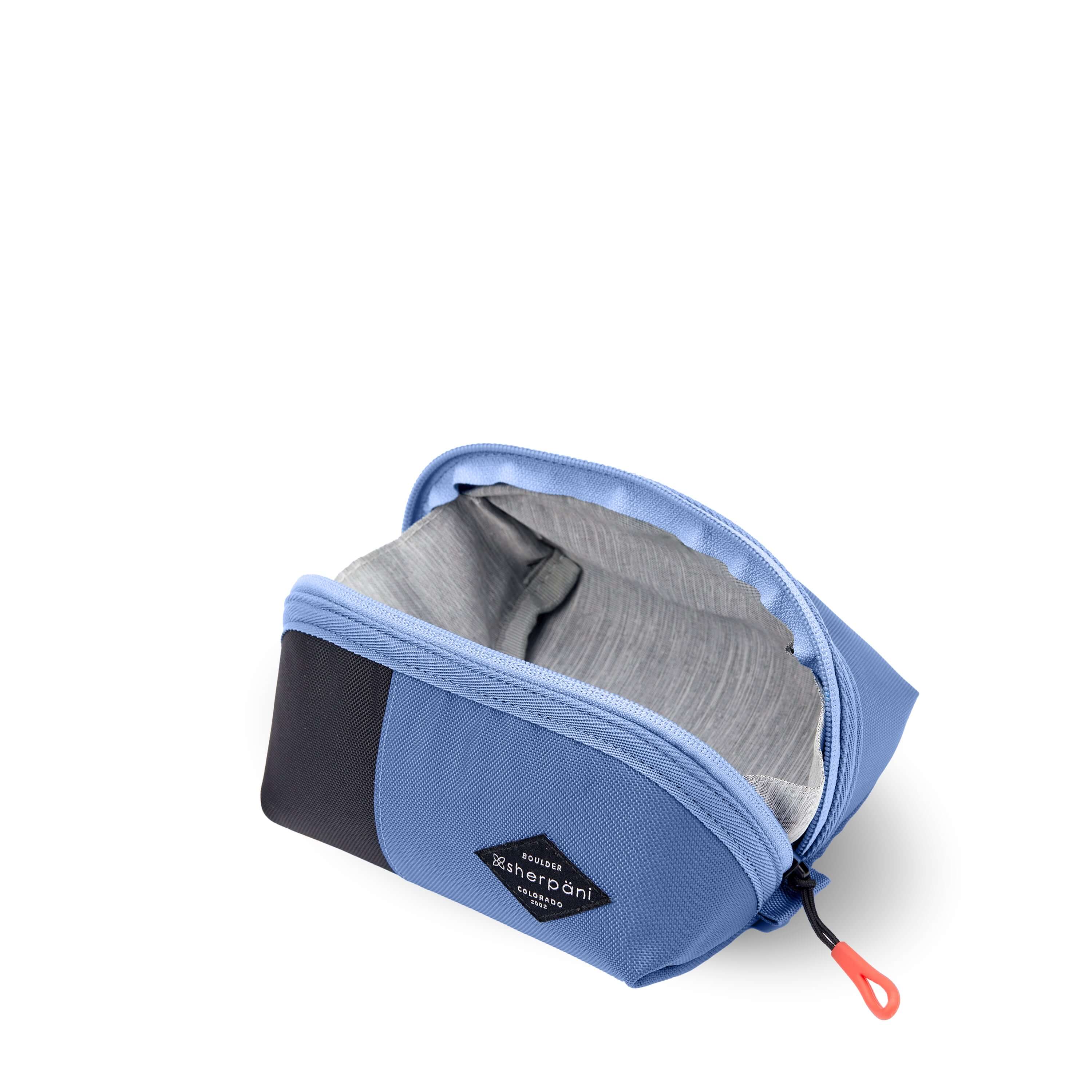 Top view of Sherpani travel accessory the Harmony in Pacific Blue. The pouch is unzipped to reveal a light gray interior. 