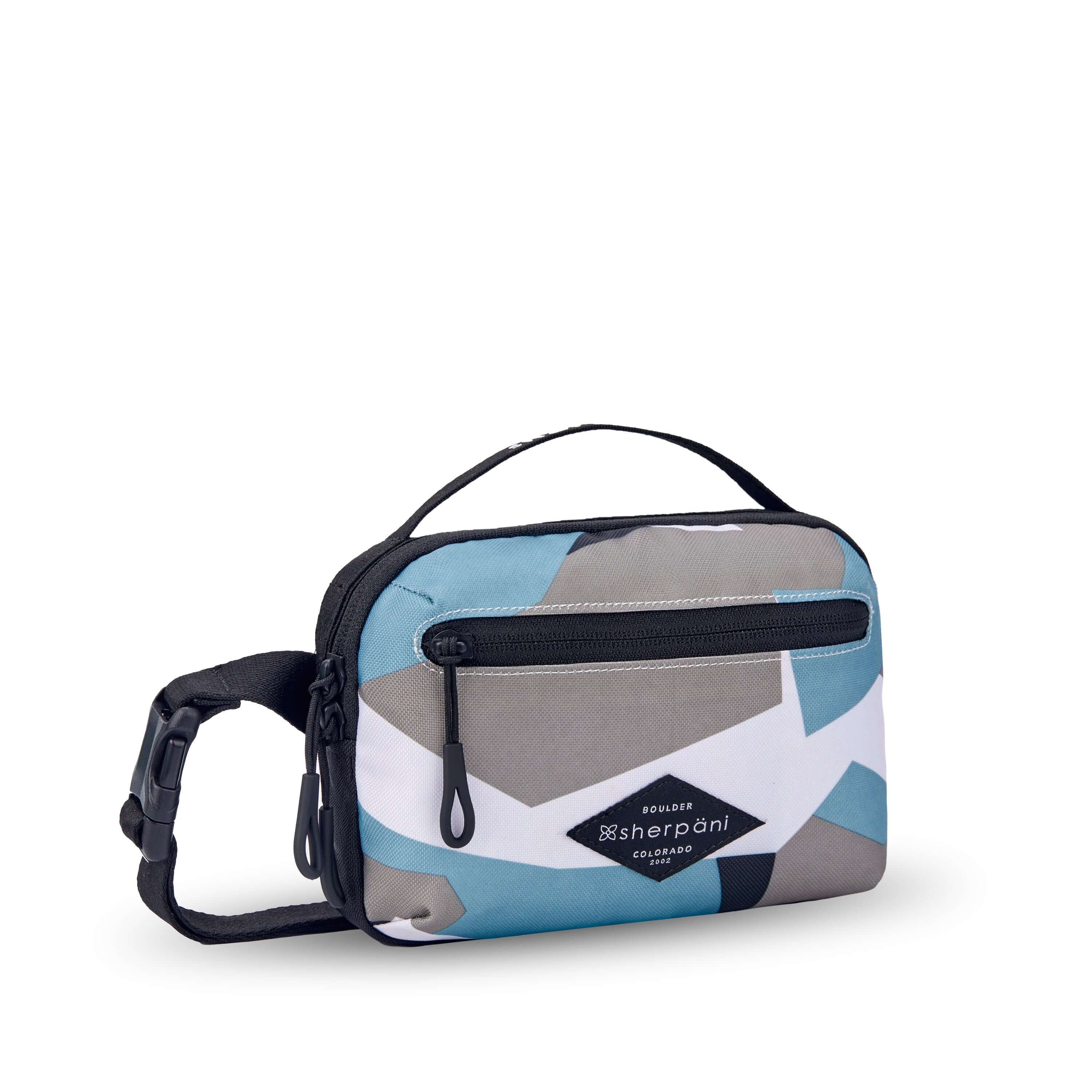 Angled front view of Sherpani’s fanny pack, the Hyk in Summe Camo. The bag is two toned, the front half is a camouflage pattern of light blue, white and gray, and the back half is black. There is an external zipper pocket on the front of the bag. Easy pull zippers are accented in black. The fanny pack features an adjustable strap with a buckle. #color_summer camo