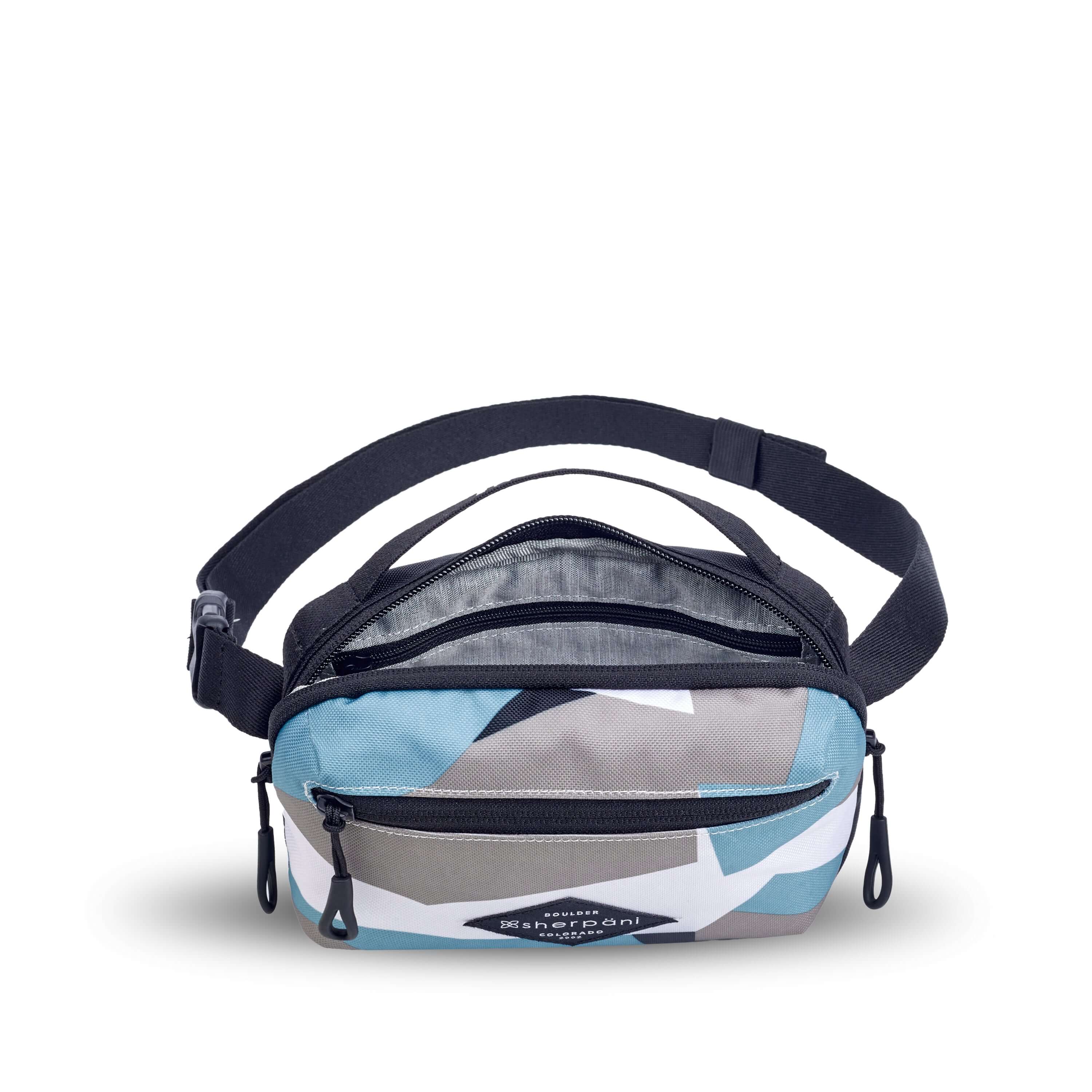 Top view of Sherpani's fanny pack, the Hyk in Summer Camo. The main zipper compartment is open to reveal a light gray interior and an internal zipper pocket. 