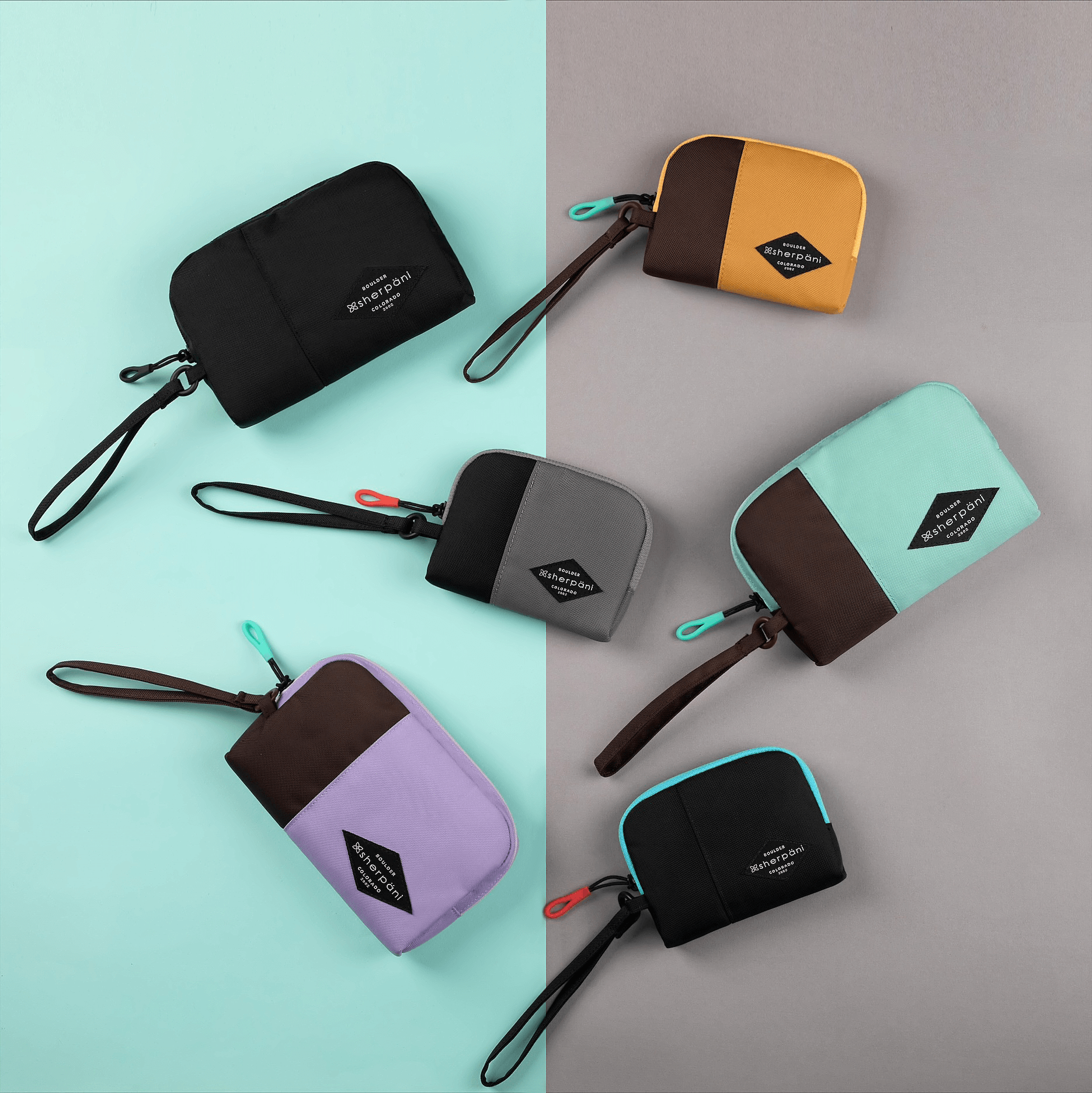 Top view of six Jolie travel pouches on a green and gray background. Clockwise form upper left: medium size Jolie in Raven, small size Jolie in Sundial, medium size Jolie in Seagreen, small size Jolie in Chromatic, medium size Jolie in Lavender, small size Jolie in Stone. 