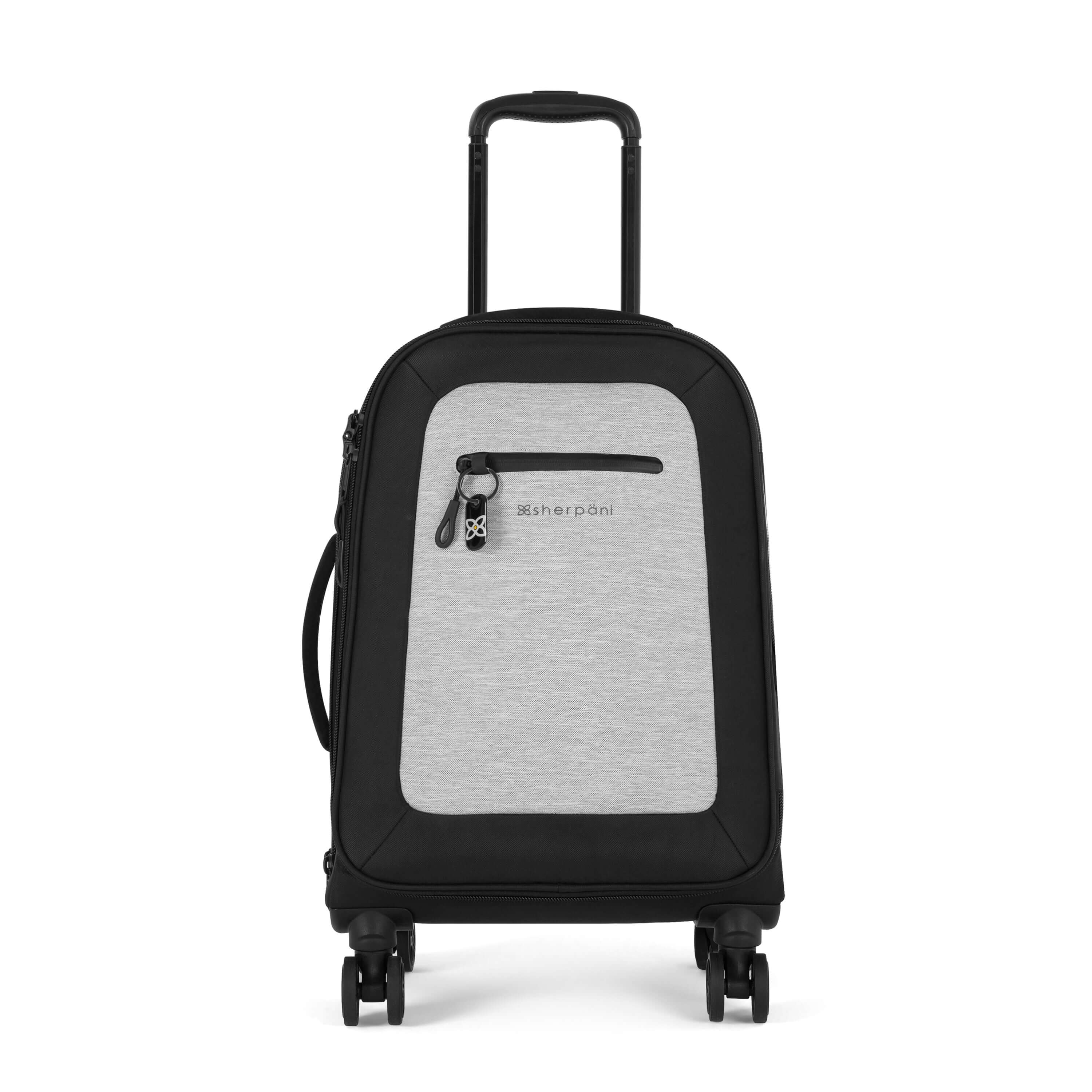 Flat front view of Sherpani's Anti-Theft luggage the Latitude in Sterling. The suitcase has a soft shell exterior made from recycled plastic bottles and features vegan leather accents in black. There is a main zipper compartment, an expansion zipper and an external pocket on the front with a locking zipper and a ReturnMe tag. On the top of the suitcase sits a retractable luggage handle. On the side sits an easy-access handle. At the bottom are four 360-degree spinner wheels for rolling. 