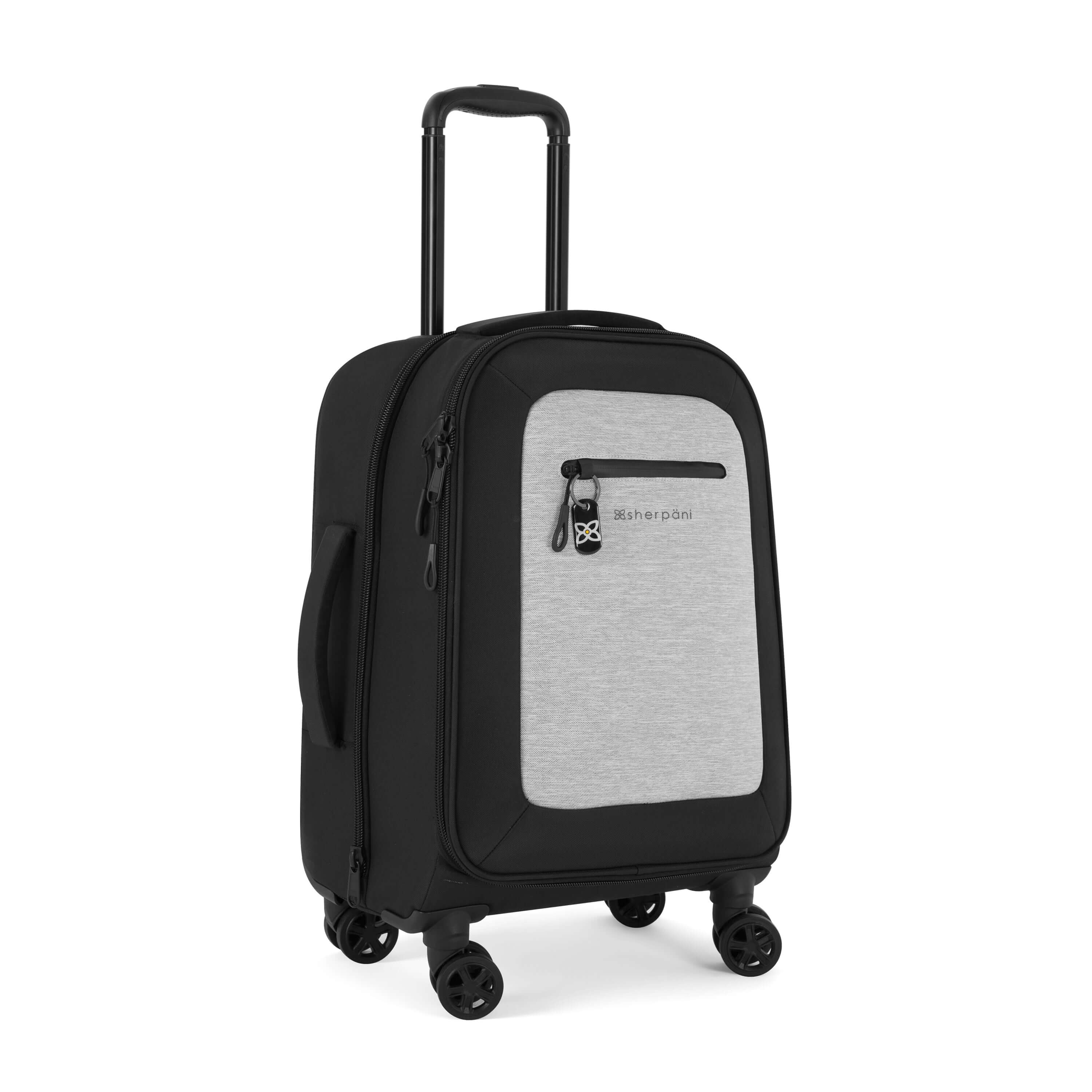 Angled front view of Sherpani's Anti-Theft luggage the Latitude in Sterling. The suitcase has a soft shell exterior made from recycled plastic bottles and features vegan leather accents in black. There is a main zipper compartment, an expansion zipper and an external pocket on the front with a locking zipper and a ReturnMe tag. On the top of the suitcase sits a retractable luggage handle. On the side sits an easy-access handle. At the bottom are four 360-degree spinner wheels for rolling. 