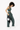 Model holding the Sherpani sling bag, the Metro AT in Sterling by its top handle.  #color_sterling-metal