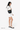 Model wearing the Sherpani crossbody, the Milli in Chromatic, holding the strap with one hand and standing sideways #color_chromatic