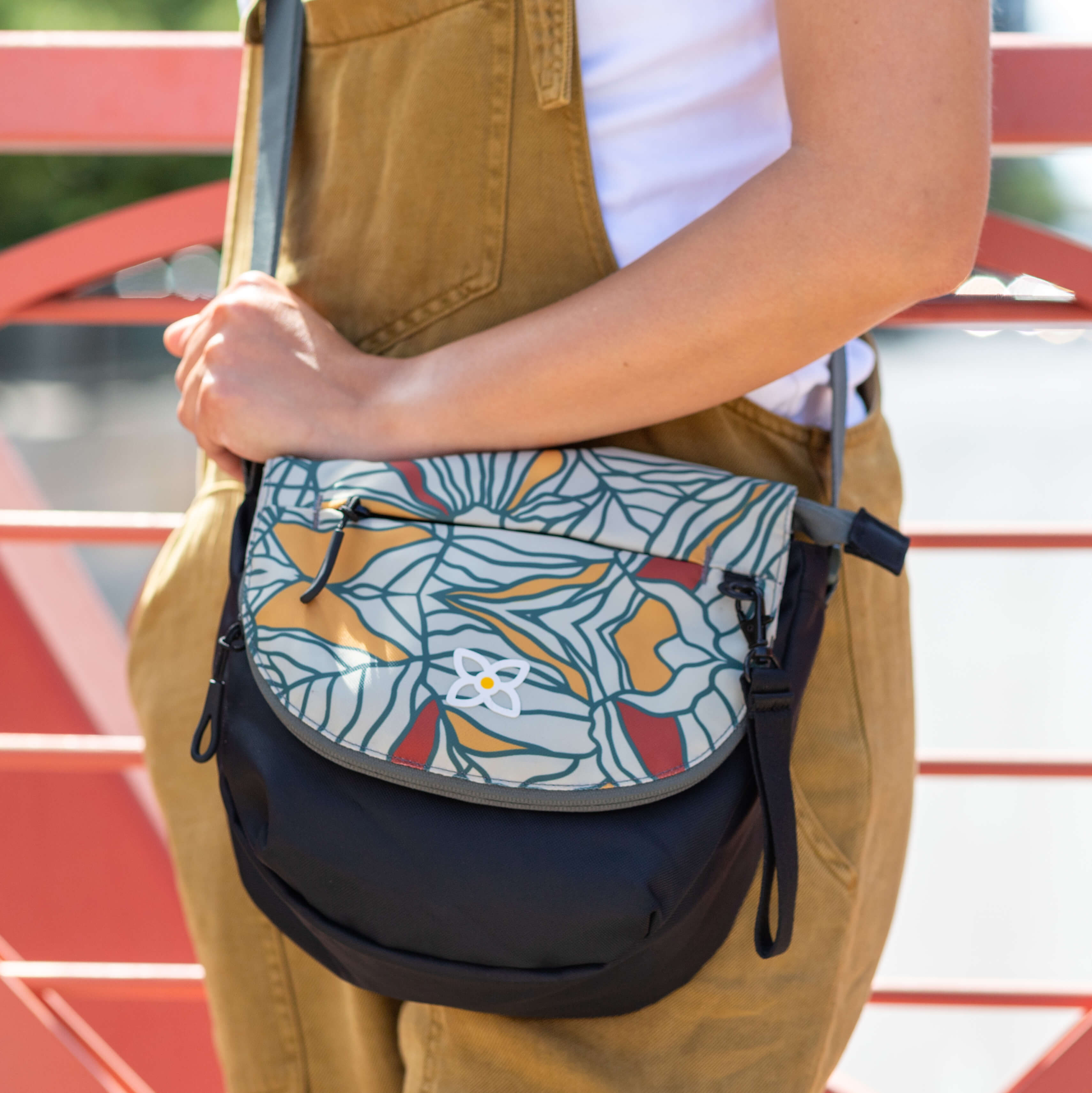 A woman standing outside is wearing Sherpani crossbody messenger bag, the Milli in Fiori. 