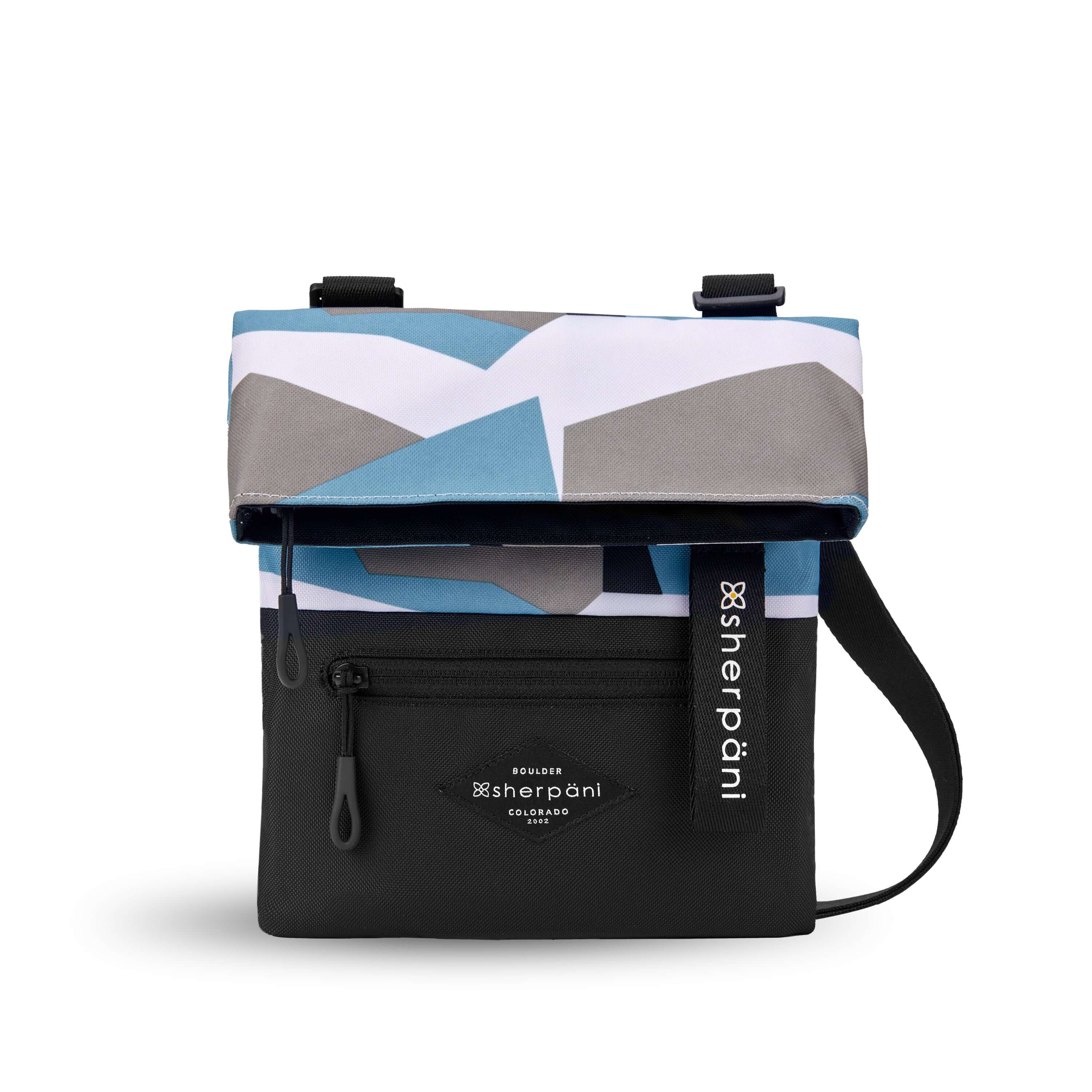 Flat front view of Sherpani crossbody, the Pica in Summer Camo. The bag is two toned: the top half is a camouflage pattern of light blue, gray and white and the bottom half is black. There is an external zipper pocket on the front panel. Easy pull zippers are accented in black. The top of the bag folds over creating a signature look. A branded Sherpani keychain is clipped to the upper right corner. The bag has an adjustable crossbody strap. 