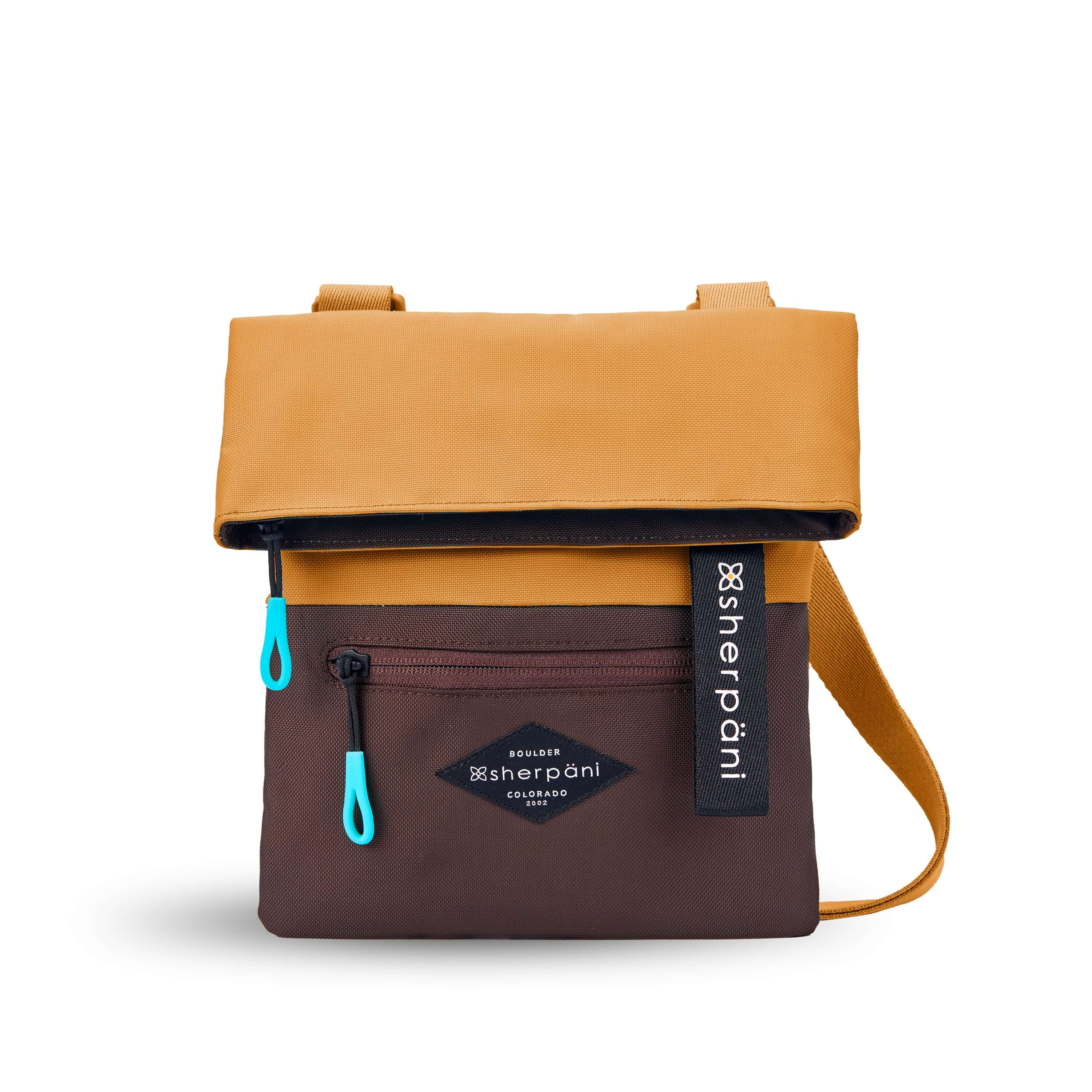 Flat front view of Sherpani crossbody, the Pica in Sundial. The bag is two toned: the top half is burnt yellow and the bottom half is brown. There is an external zipper pocket on the front panel. Easy pull zippers are accented in aqua. The top of the bag folds over creating a signature look. A branded Sherpani keychain is clipped to the upper right corner. The bag has an adjustable crossbody strap. 