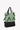 Angled front view of Sherpani Anti-Theft bag, the Tempest AT in Basil. The bag features a soft green front panel with black accents. This Anti-Theft reversible tote includes security features for safe travels and an adjustable backpack strap that can convert the Tempest to a left-handed design. #color_basil-metal