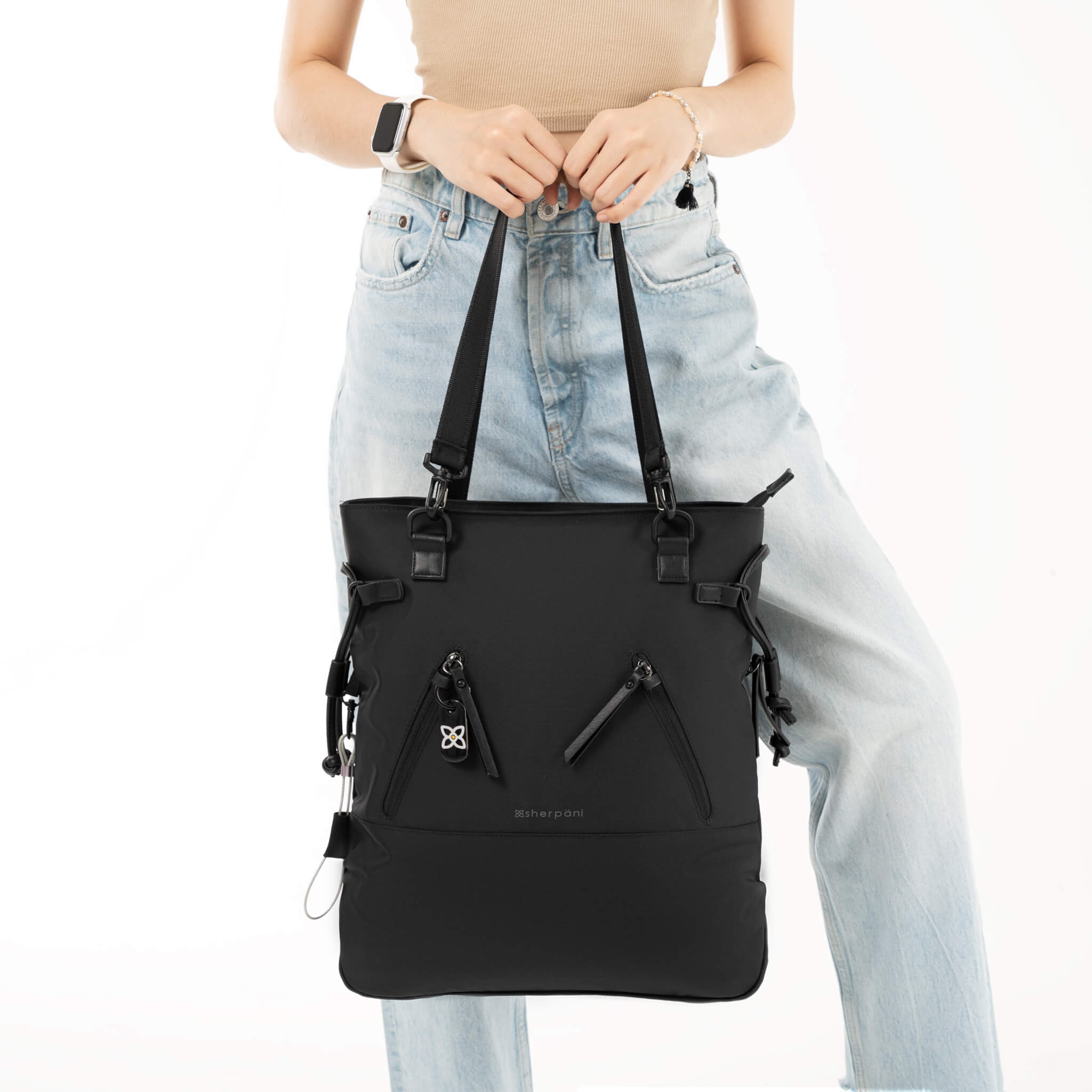 Model holding the tote handles of Sherpani Anti-Theft bag, the Tempest in Carbon. 