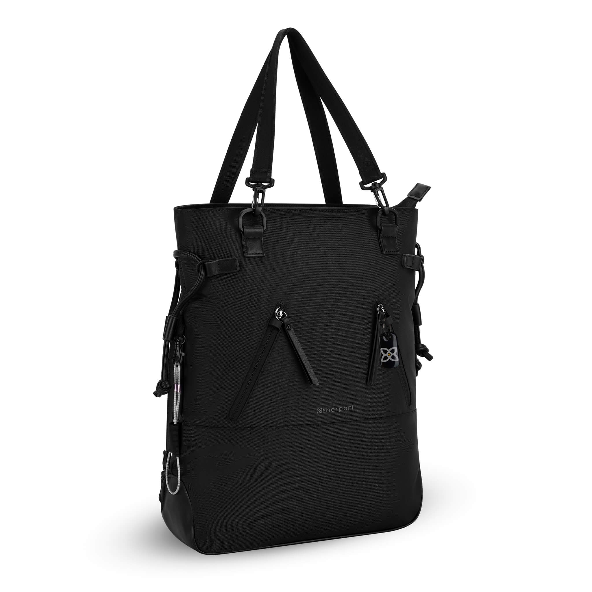 Angled front view of Sherpani Anti-Theft tote backpack, the Tempest in Carbon. The convertible bag includes RFID protection, locking zipper pockets, adjustable straps, and a trolley sleeve. 