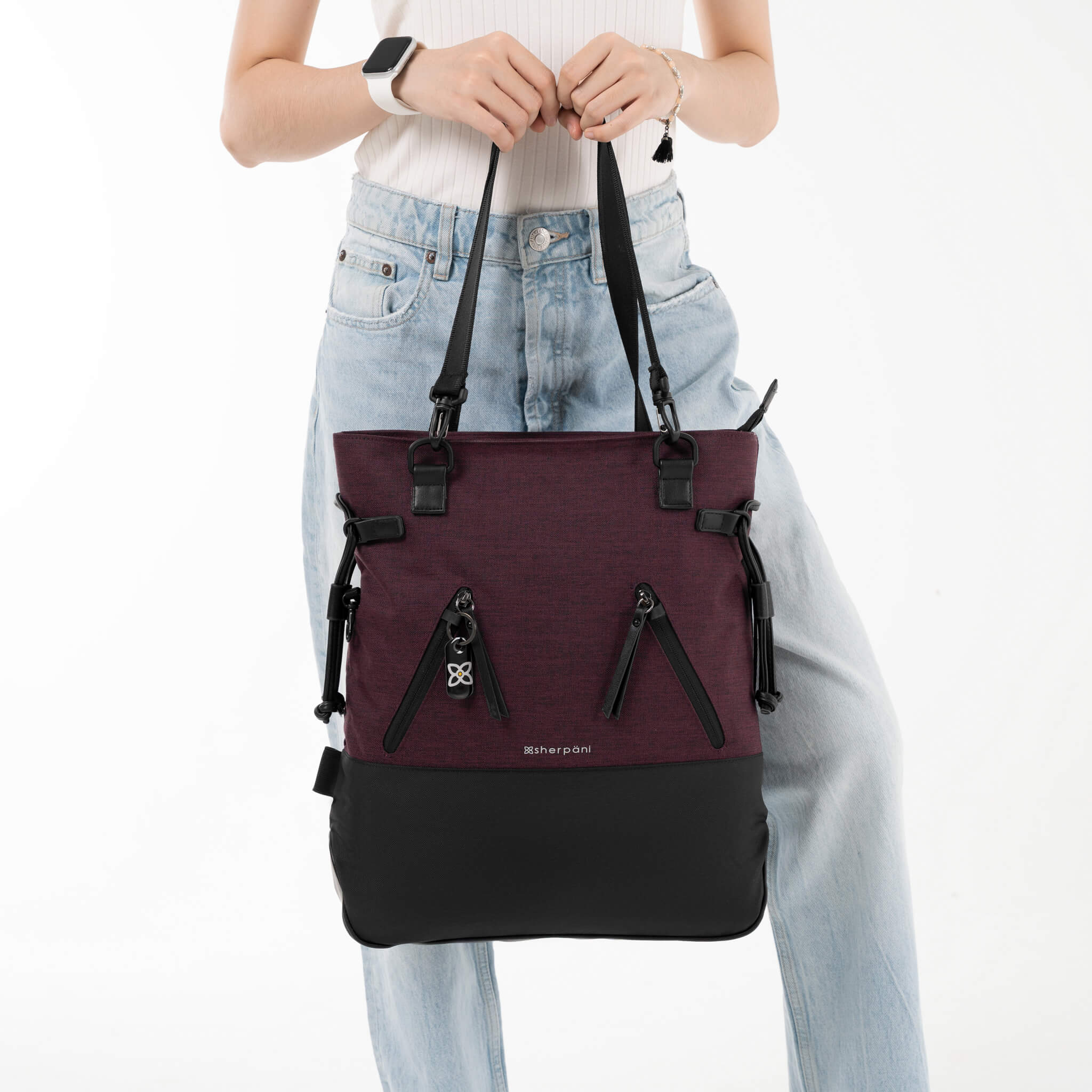 A model holding the Tempest in Merlot by the convertible tote bag handles. 