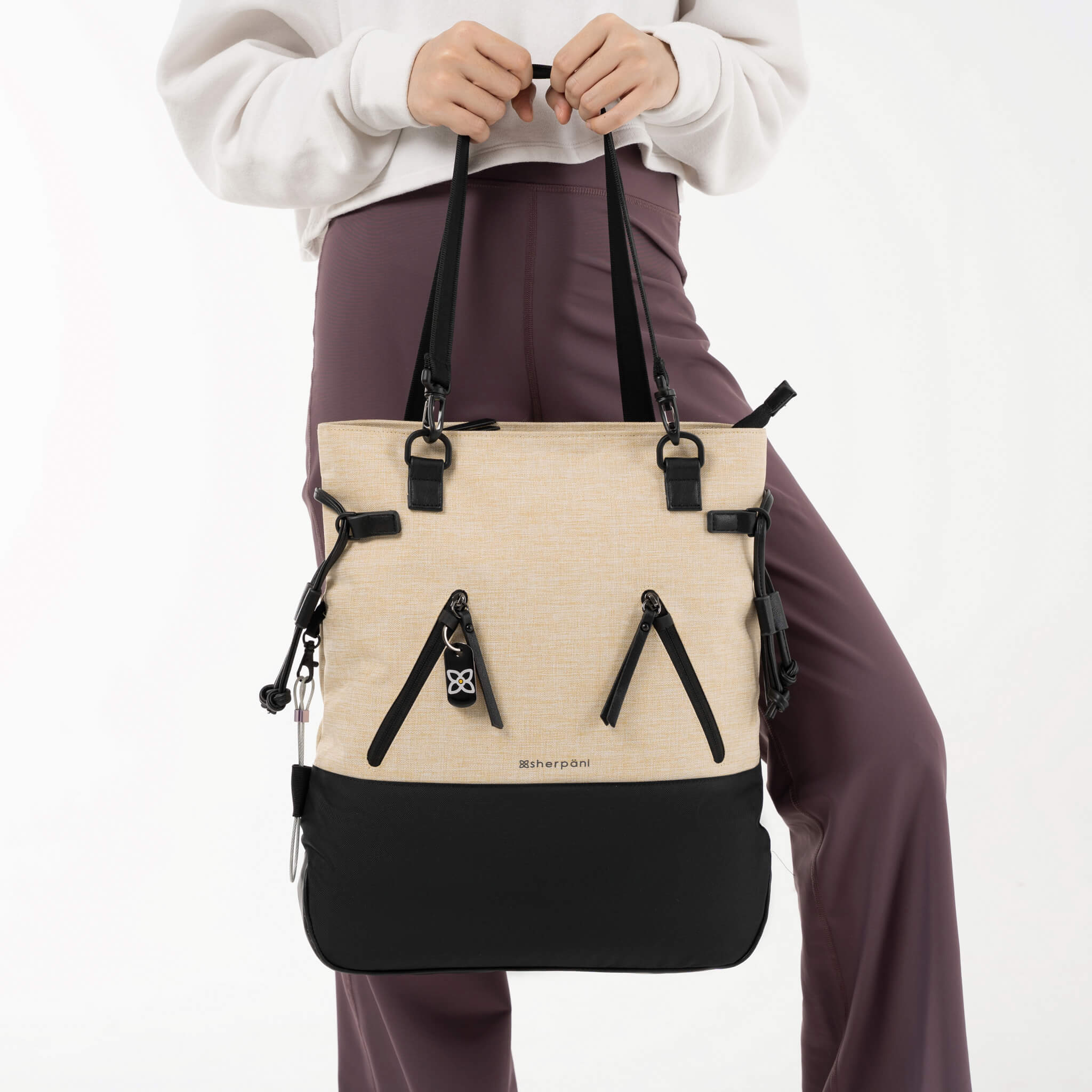 Model holding Sherpani Anti-Theft Tempest by the tote bag handles. 