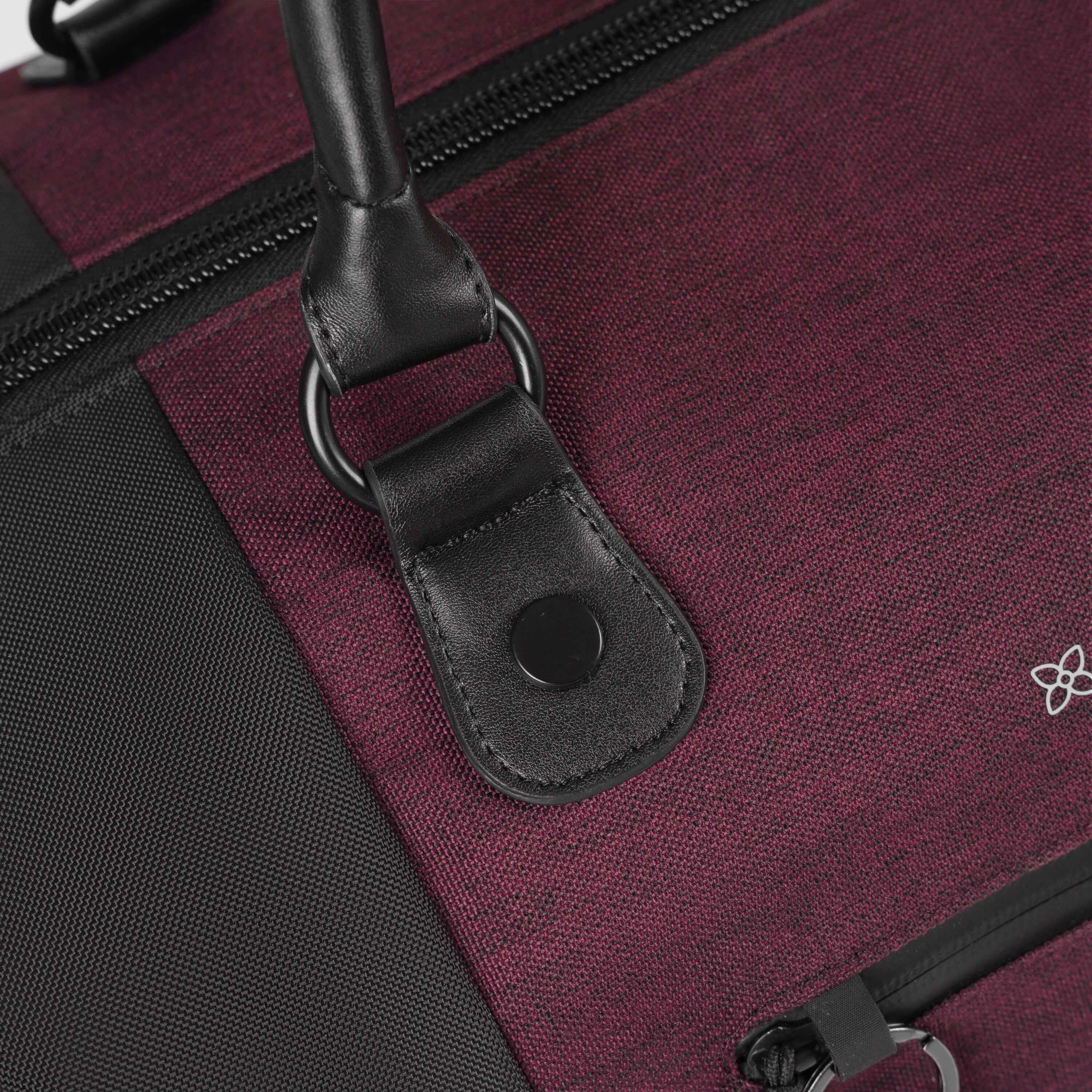 Close up view of vegan leather accents on tote handles of Sherpani's Anti-Theft rolling duffle the Trip in Merlot. 