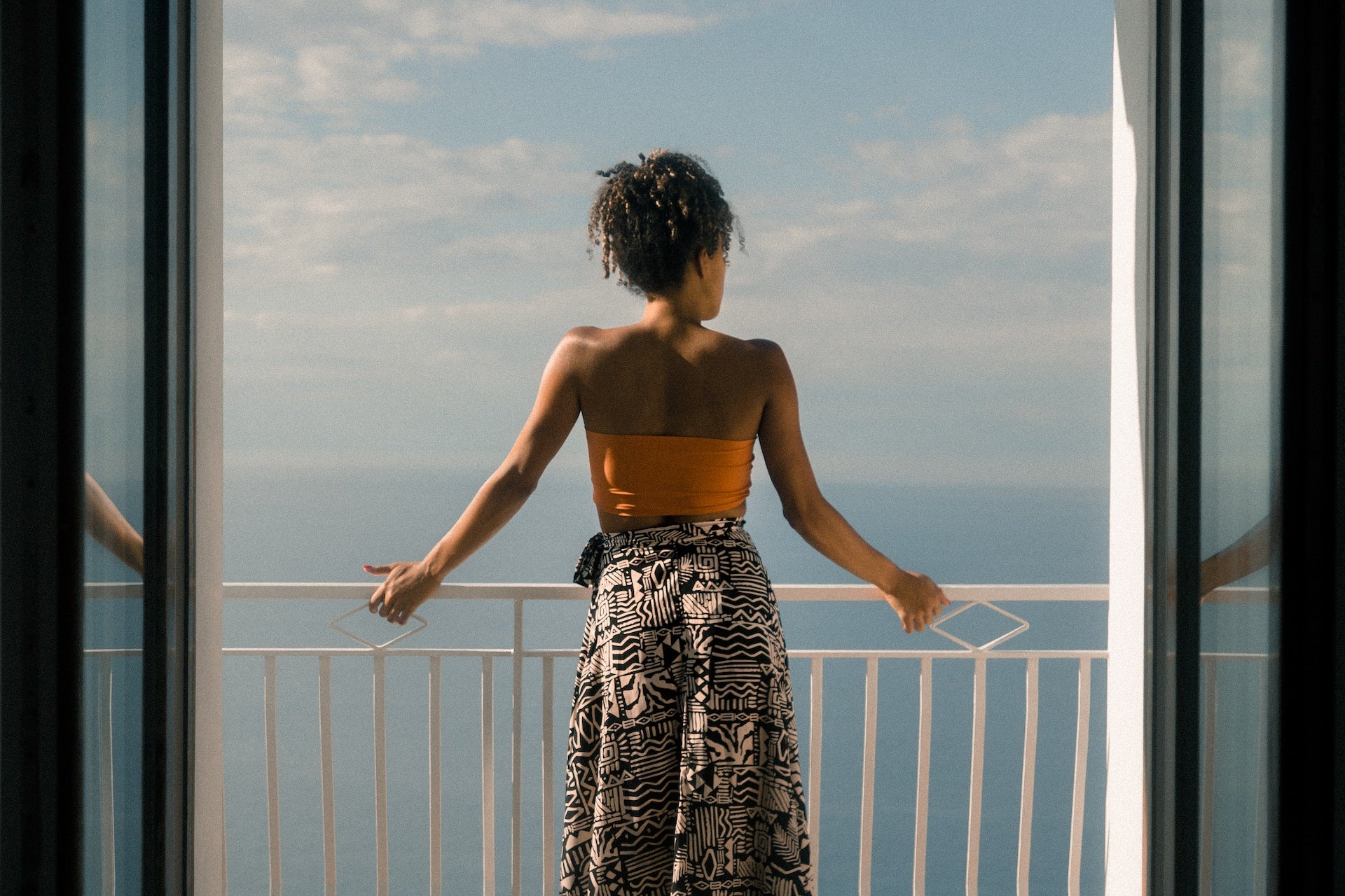 A woman standing on a balcony looking out over the ocean.