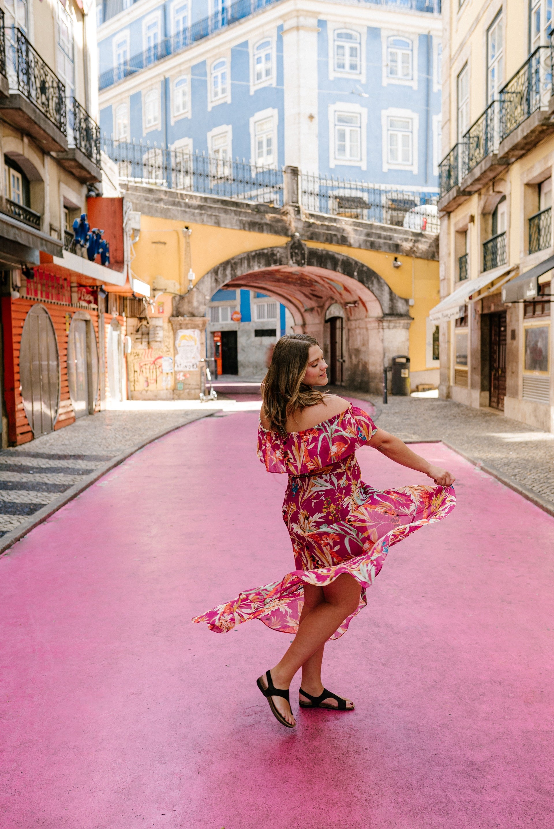 A woman twirling in a pink dress on a matching pink street