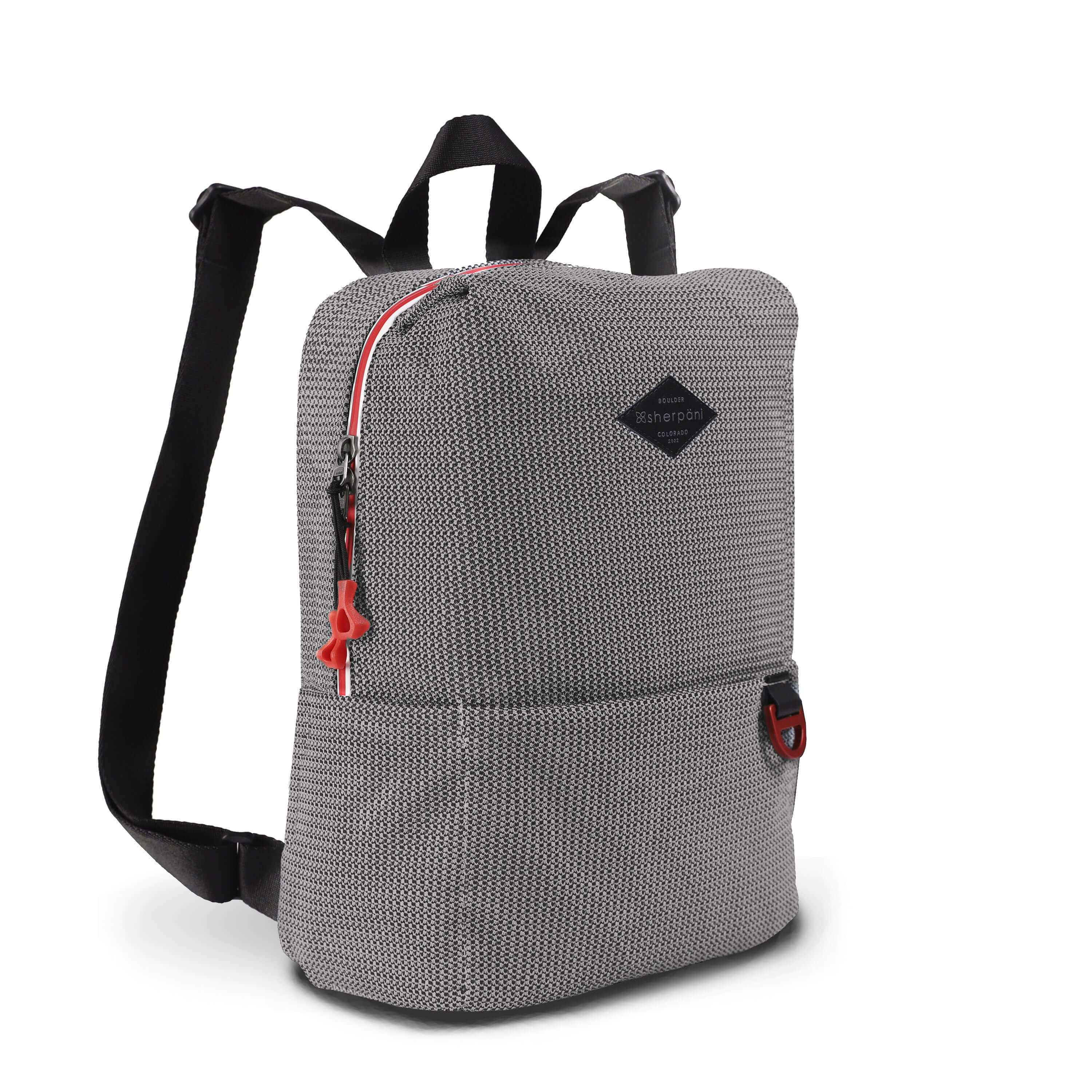 Angled front view of Sherpani mesh backpack, the Adaline. It has a black and white mesh pattern and features red pops of color on the accent buckle and easy-pull zipper. The bag has black adjustable backpack straps and a tote handle for easy carrying.