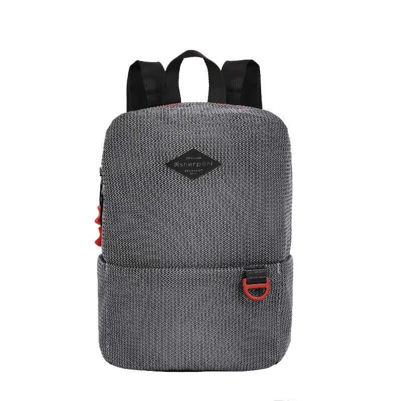 Flat front view of Sherpani mesh backpack, the Adaline. It has a black and white mesh pattern and features red pops of color on the accent buckle and easy-pull zipper. The bag has black adjustable backpack straps and a tote handle for easy carrying.