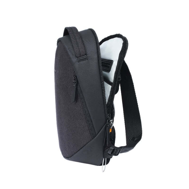 Side view of Sherpani&#39;s Anti-Theft backpack, the Presta in Black. The main zipper compartment is open to reveal a light colored interior and an internal zipper pocket. There is an external zipper pocket near the front, an easy-access handle at the top, and adjustable/padded backpack straps at the rear. A chair loop lock is clipped near the bottom, and held in place by a fabric tab.