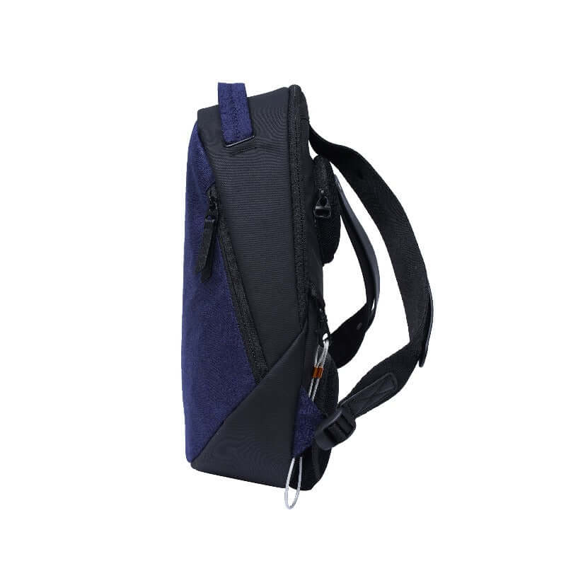 Side view of Sherpani&#39;s Anti-Theft backpack, the Presta in Midnight Blue, with black accents. There is an external zipper pocket near the front, an easy-access handle at the top, and adjustable/padded backpack straps at the rear. A chair loop lock is clipped near the bottom, and held in place by a fabric tab.