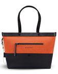 Flat front view of Sherpani's Anti-Theft tote, the Cali AT in Copper, with vegan leather accents in black. There is an external compartment on the front of the bag with a locking zipper. A chair loop lock is clipped to the side of the bag and is held in place by an elastic tab.