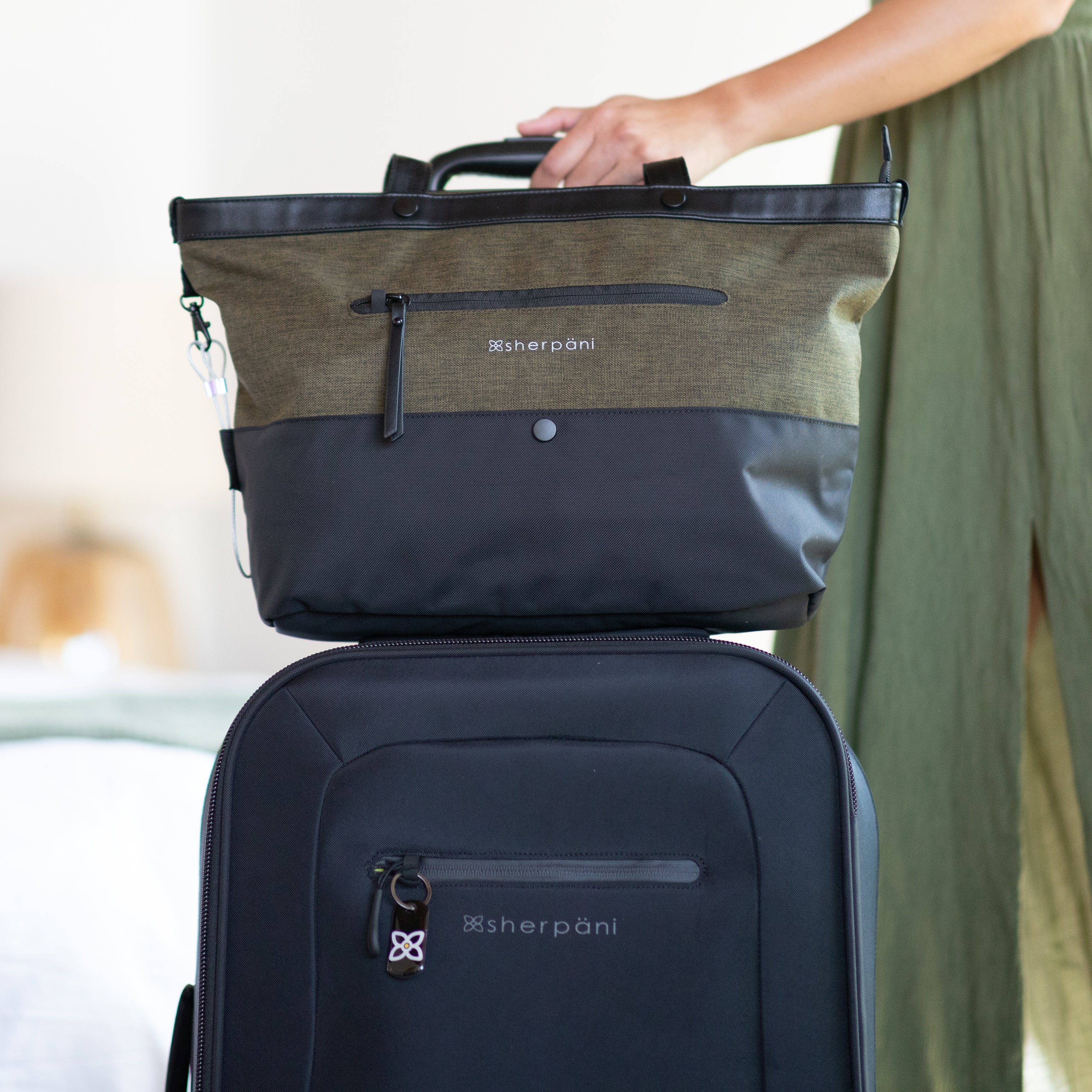 Sherpani Anti-Theft tote bag, the Cali in Loden, sitting on top of Sherpani soft-shell carry-on luggage, the Latitude, utilizing the luggage pass through feature. 