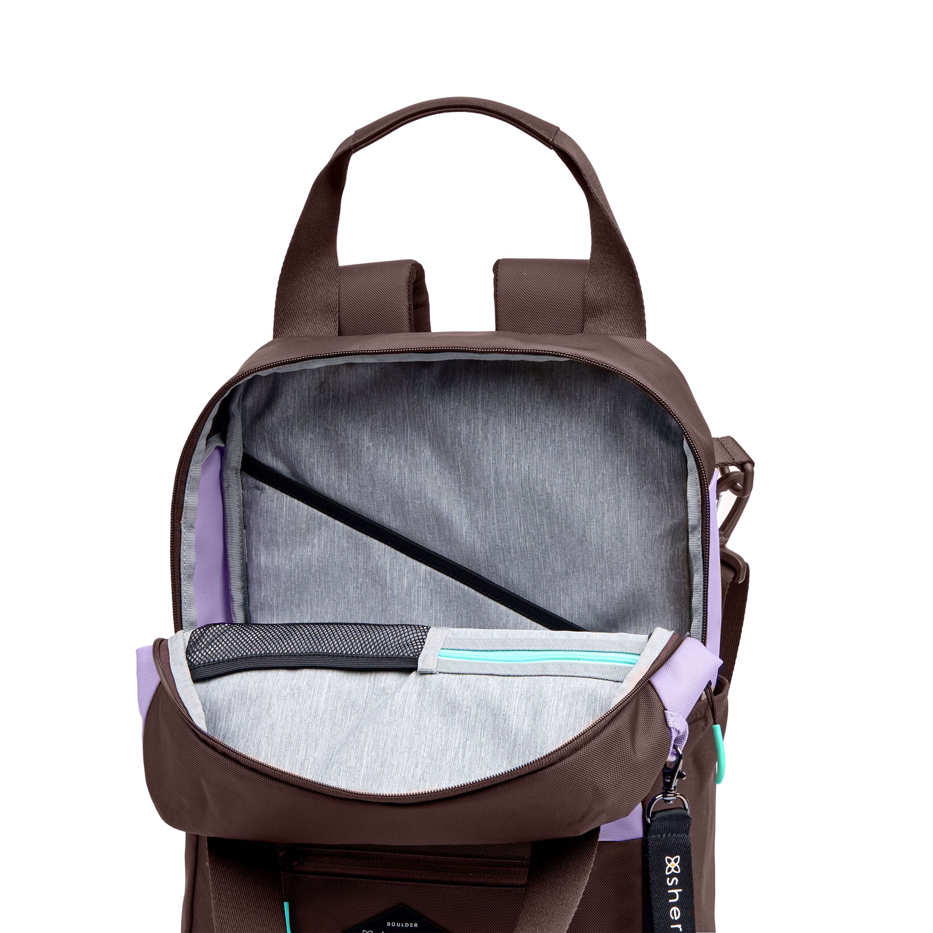 Front view of Sherpani's three-in-one bag, the Camden in Lavender. The main zipper compartment is open to reveal a light gray interior with a padded laptop sleeve, zipper pocket and mesh pocket. 