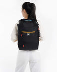 A model wearing Sherpani convertible travel bag, the Camden in Cool Chromatic, as an ergonomic backpack.