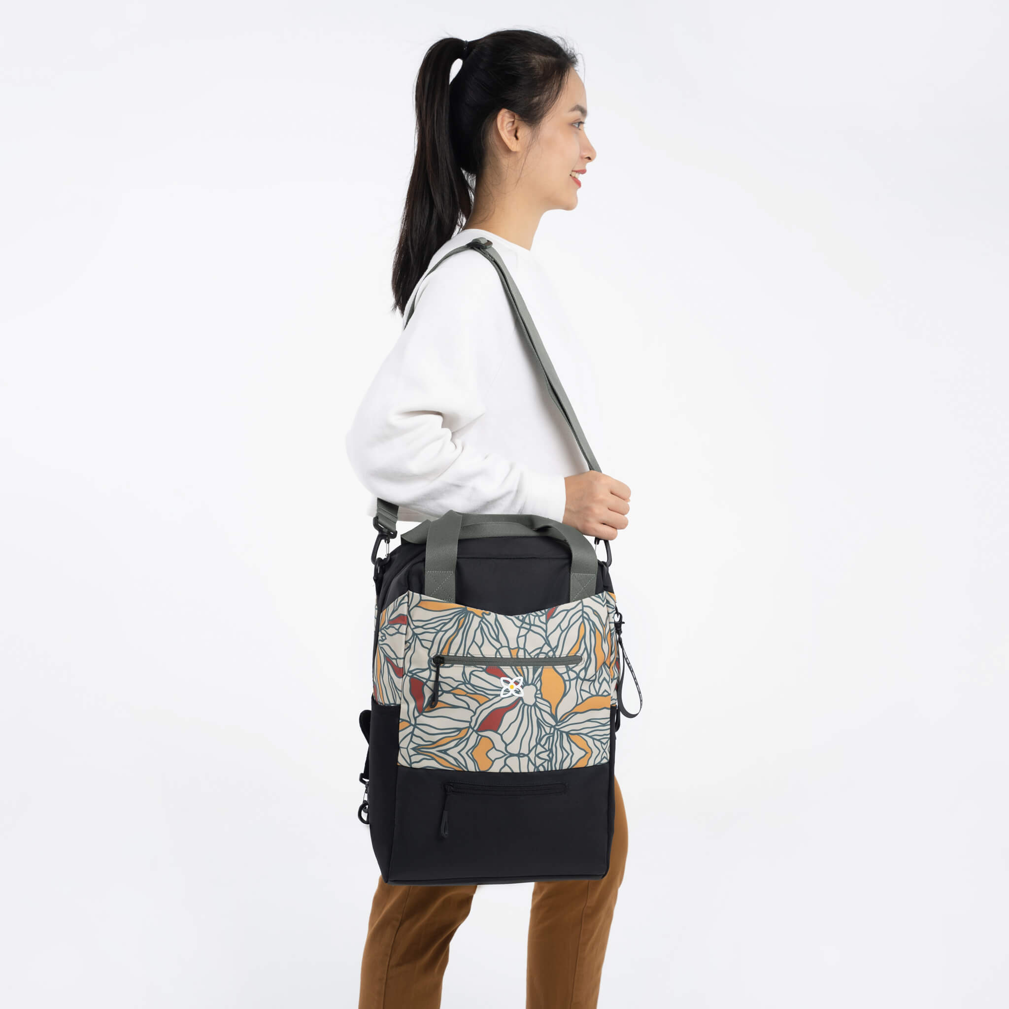 A model with Sherpani 3-in-1 large crossbody purse, the Camden in Fiori. She is using the removable purse strap to carry the Camden as a shoulder bag. 