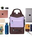 Top view of example items to fill the bag. Sherpani's three-in-one bag, the Camden in Lavender, lies in the center. It is surrounded by an assortment of items: sunglasses, car key, tablet, phone, travel books, water bottle, laptop, passport and Sherpani travel accessory the Jolie in Sundial.