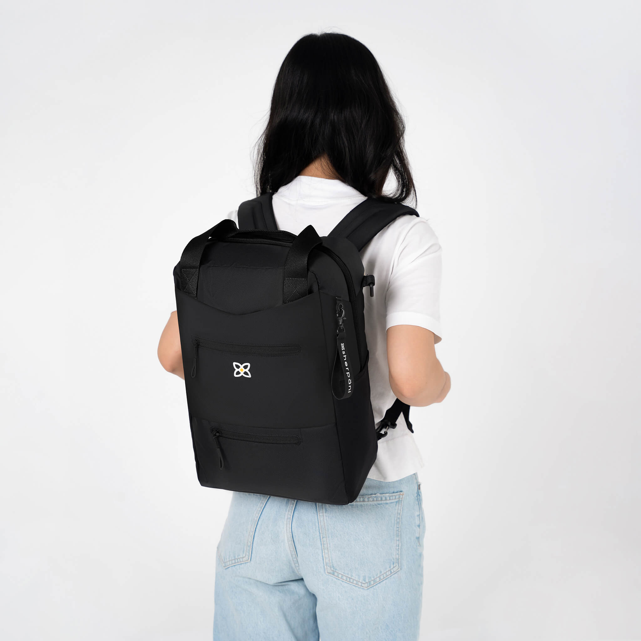 A model wearing Sherpani travel bag, the Camden in Raven, as a backpack. 