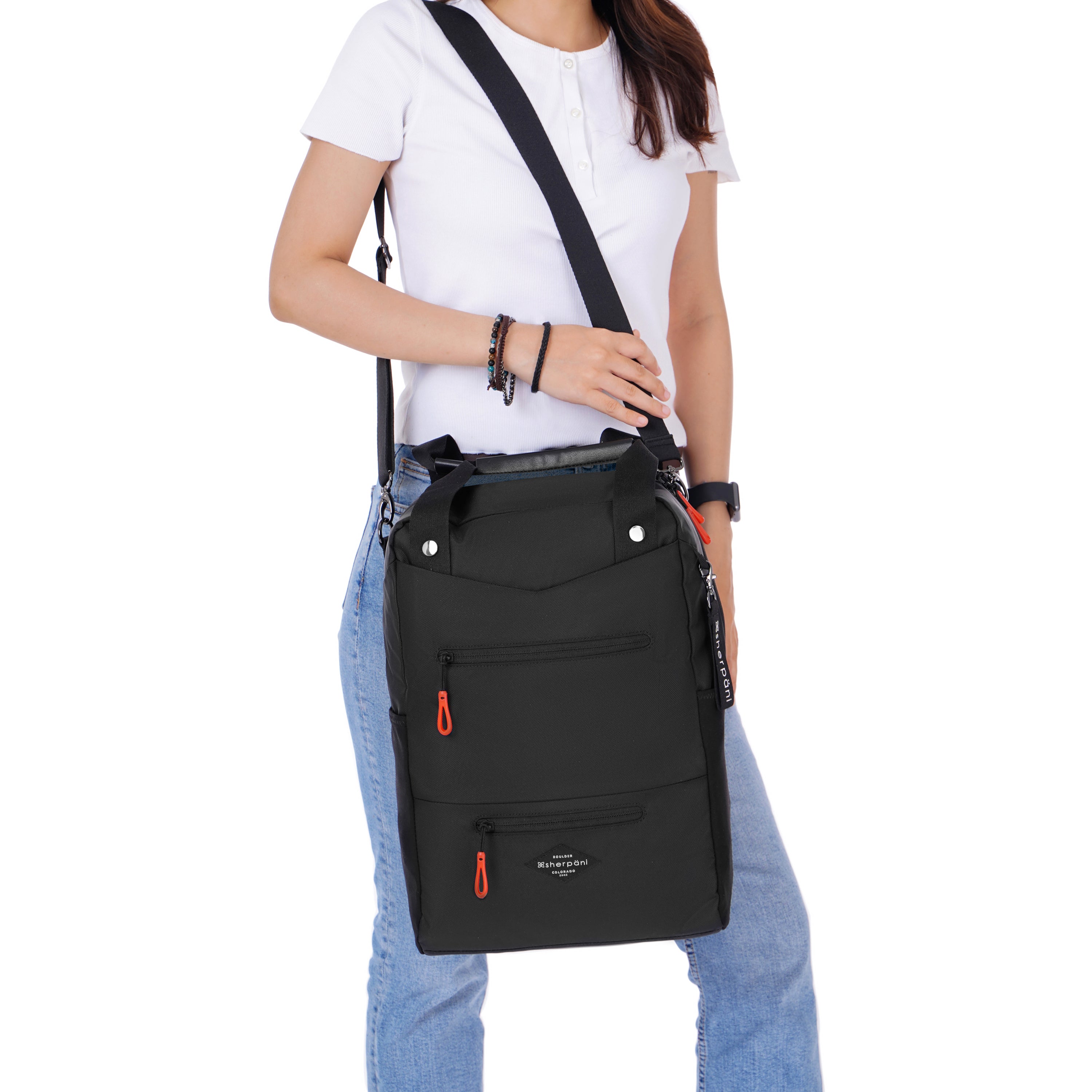 Close up view of a dark haired model. She is wearing a white tee shirt and jeans. She is carrying Sherpani's three in one bag, the Camden in Raven, as a crossbody. 