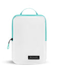 Flat front view of Compass Packing Cube in large size. The cube is white with zipper and handle accented in aqua.