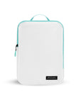 Flat front view of Compass Packing Cube in medium size. The cube is white with zipper and handle accented in aqua.