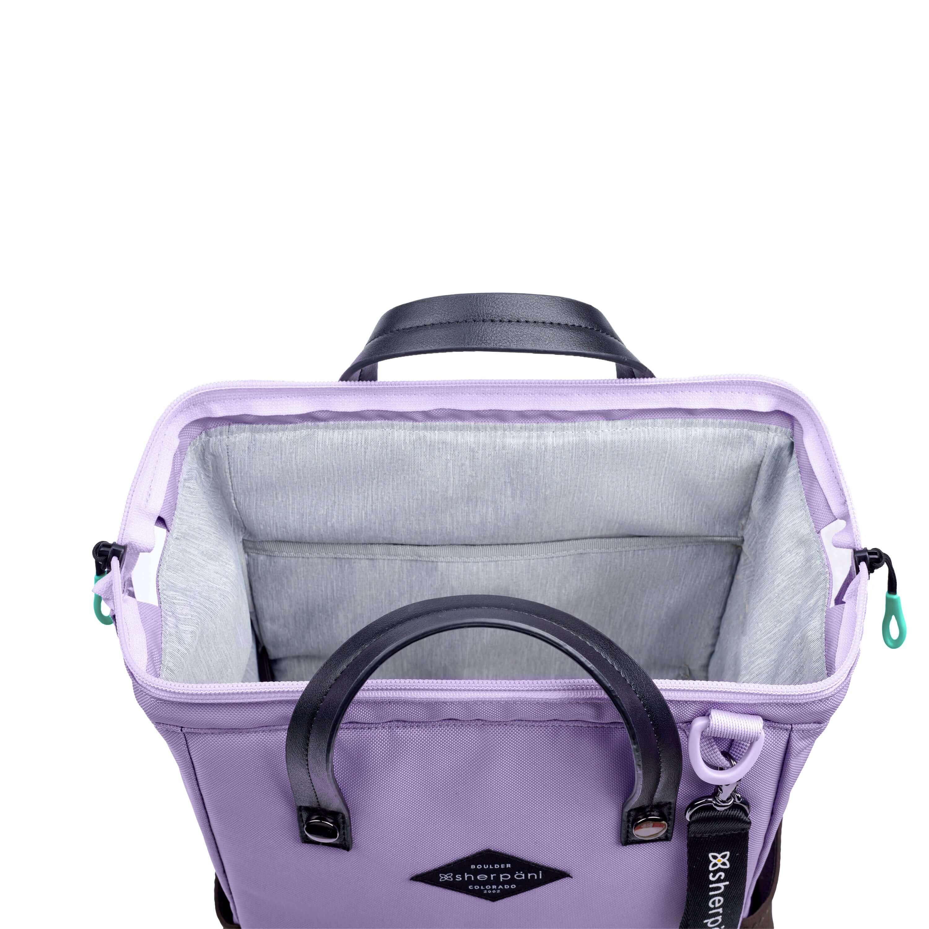 Top view of Sherpani three-in-one bag, the Dispatch in Lavender. The main zipper compartment is open to reveal a doctor bag style opening with a rectangular metal frame. The inside of the bag is light gray and features an internal pouch. 