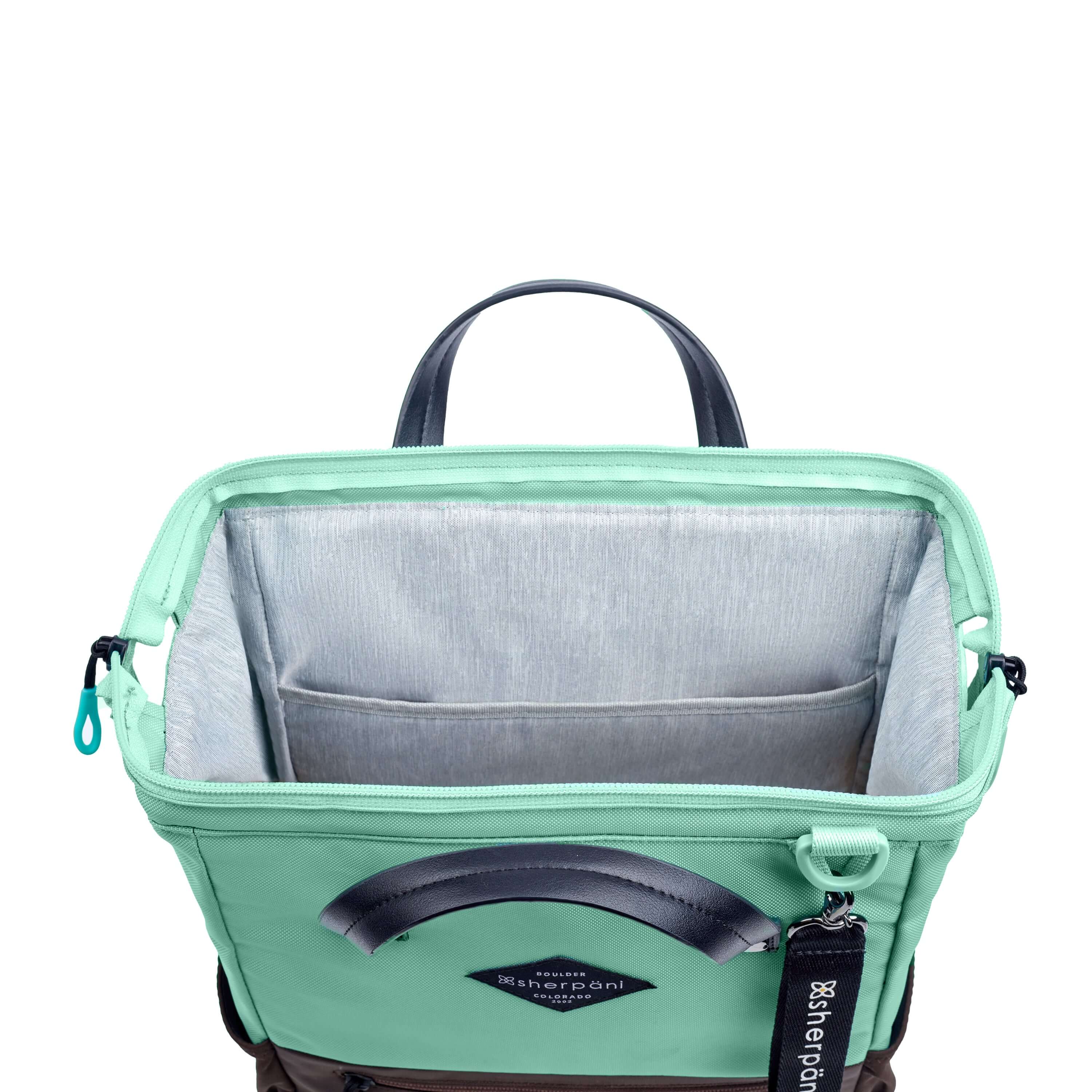 Top view of Sherpani three-in-one bag, the Dispatch in Seagreen. The main zipper compartment is open to reveal a doctor bag style opening with a rectangular metal frame. The inside of the bag is light gray and features an internal pouch.