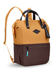 Angled front view of Sherpani three-in-one bag, the Dispatch in Sundial. The bag is two-toned: the top is burnt yellow and the bottom is brown. There is an external zipper pocket on the front panel. Easy-pull zippers are accented in aqua. A branded Sherpani keychain is clipped to the upper right corner. Elastic water bottle holders sit on either side of the bag. It has short tote handles and adjustable/detachable straps that can function for a backpack or crossbody.
