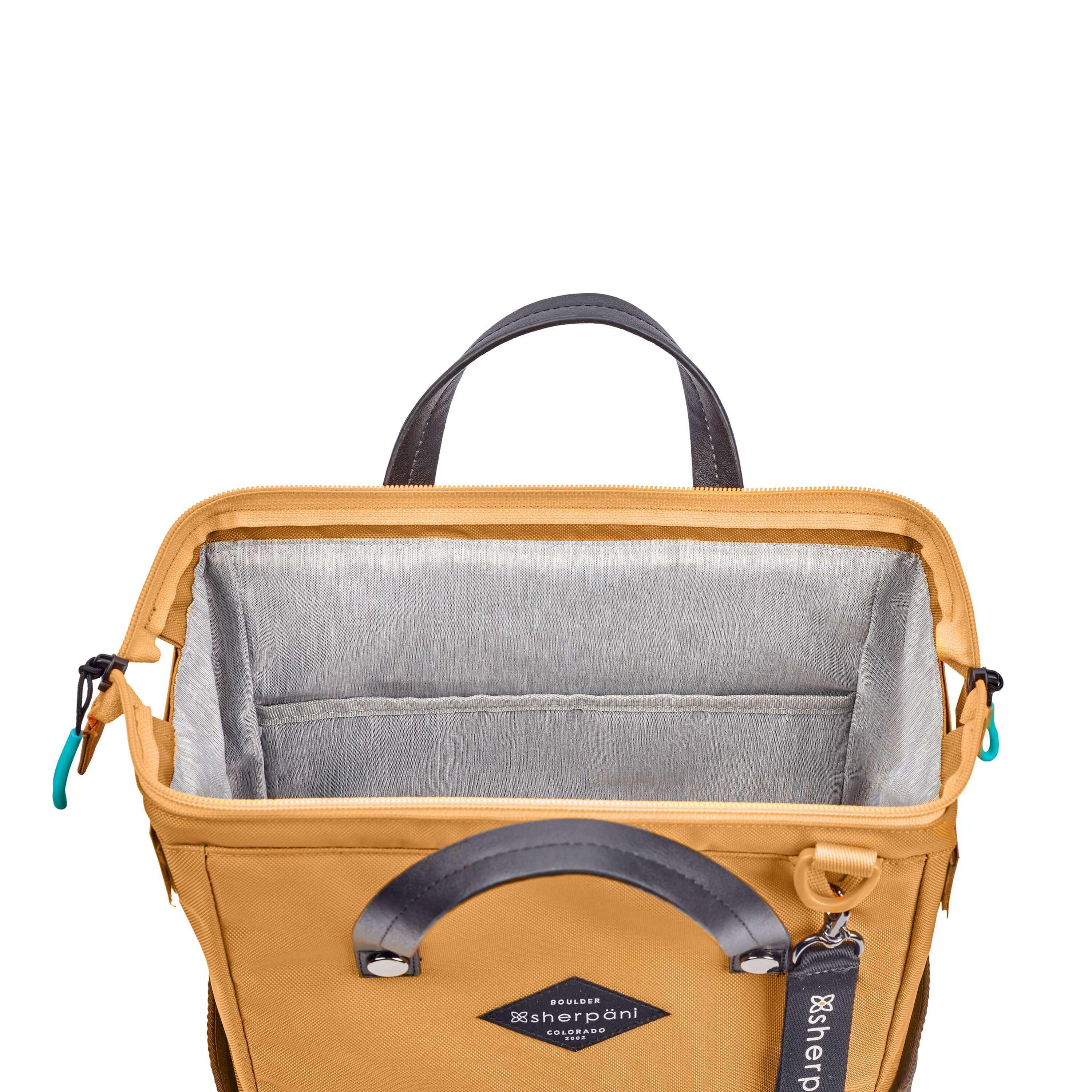 Top view of Sherpani three-in-one bag, the Dispatch in Sundial. The main zipper compartment is open to reveal a doctor bag style opening with a rectangular metal frame. The inside of the bag is light gray and features an internal pouch. 