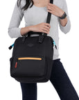 Close up view of a dark haired model facing the camera. She is wearing a gray top and black pants. She carries Sherpani three-in-one bag, the Dispatch in Chromatic, as a cossbody.