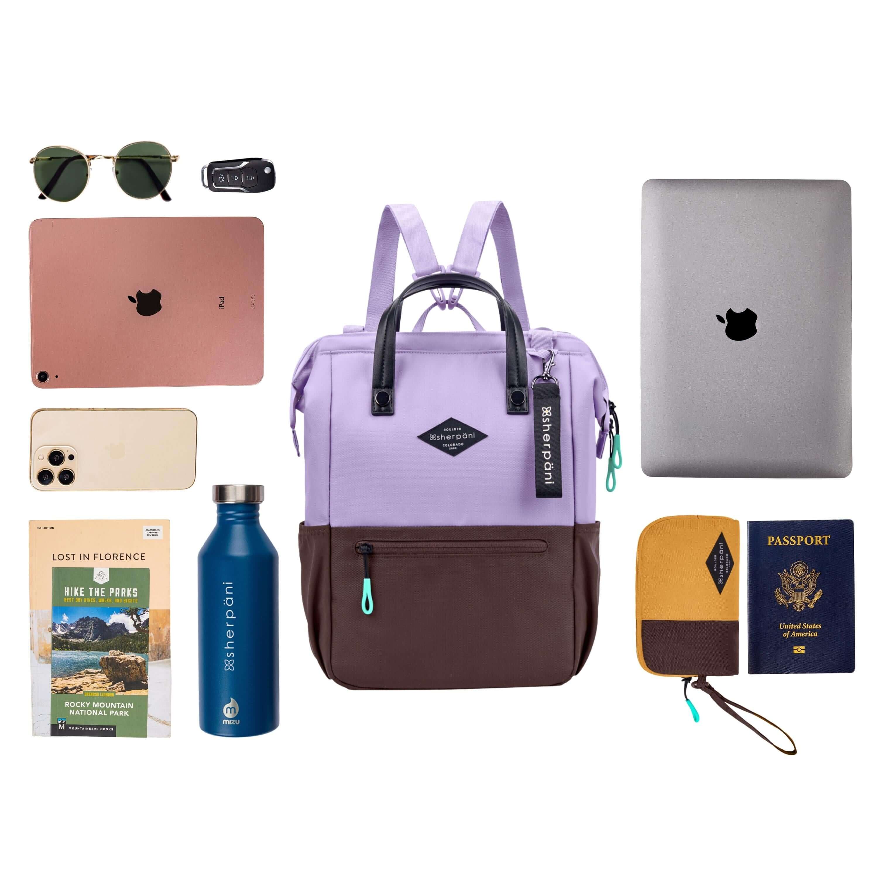 Top view of example items to fill the bag. Sherpani three-in-one bag, the Dispatch in Lavender, lies in the center. It is surrounded by an assortment of items: sunglasses, car key, laptop, phone, travel guidebooks, water bottle, laptop, passport and Sherpani travel accessory the Jolie in Sundial. 