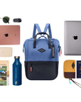 Top view of example items to fill the bag. Sherpani three-in-one bag, the Dispatch in Pacific Blue, lies in the center. It is surrounded by an assortment of items: sunglasses, car key, laptop, phone, travel guidebooks, water bottle, laptop, passport and Sherpani travel accessory the Jolie in Sundial.