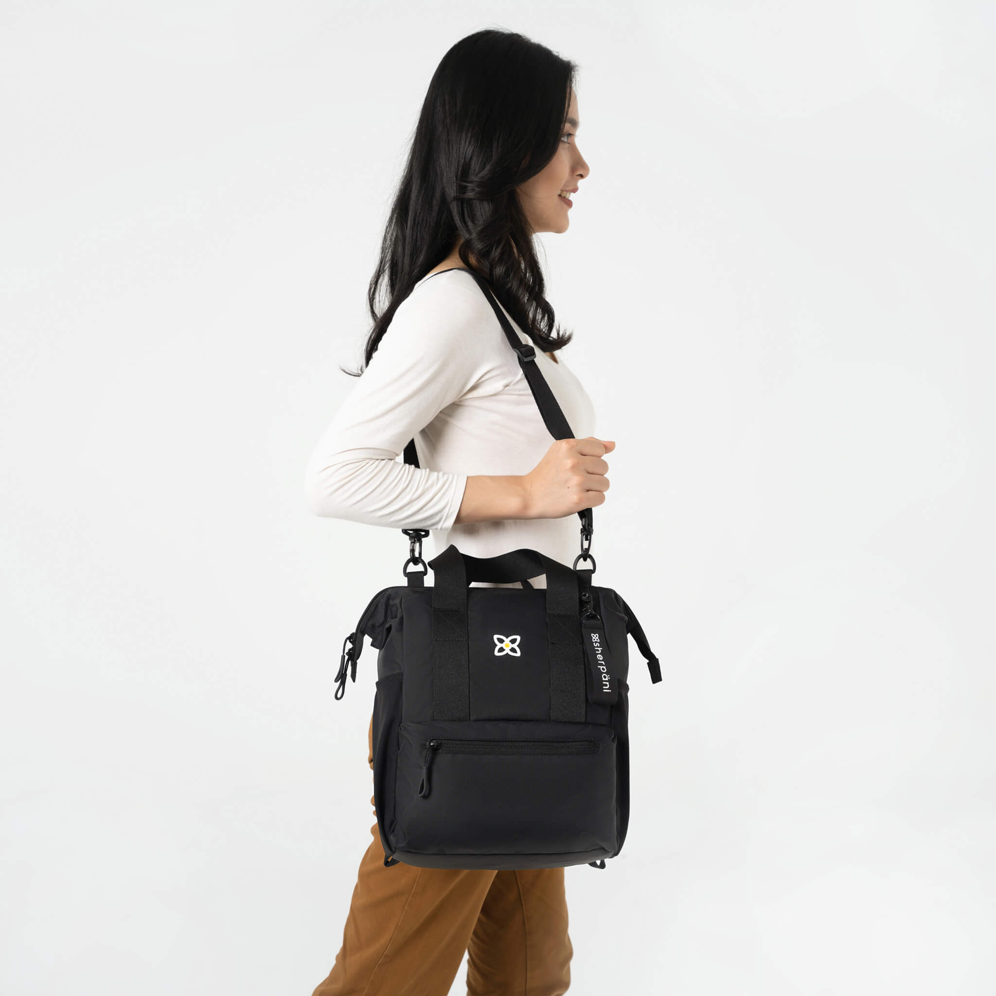A model wearing Sherpani women's travel bag, the Dispatch in Raven, over her shoulder using the adjustable crossbody strap. 