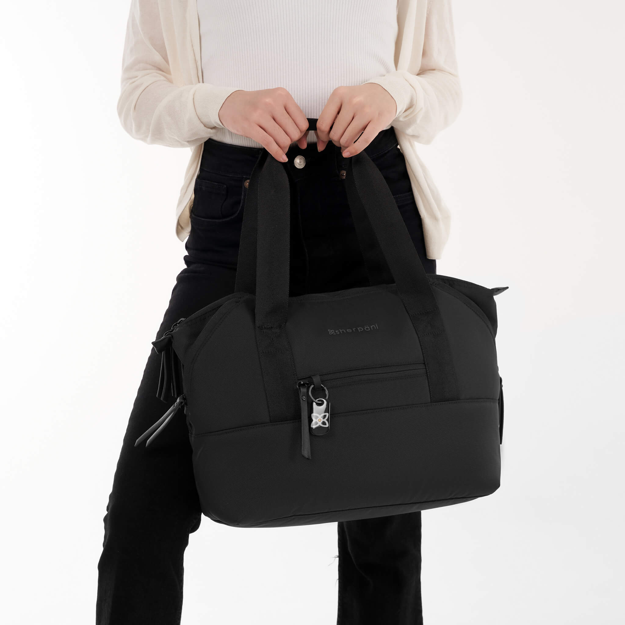 A model holding Sherpani travel tote, the Eclipse in Carbon, by the tote handles. 